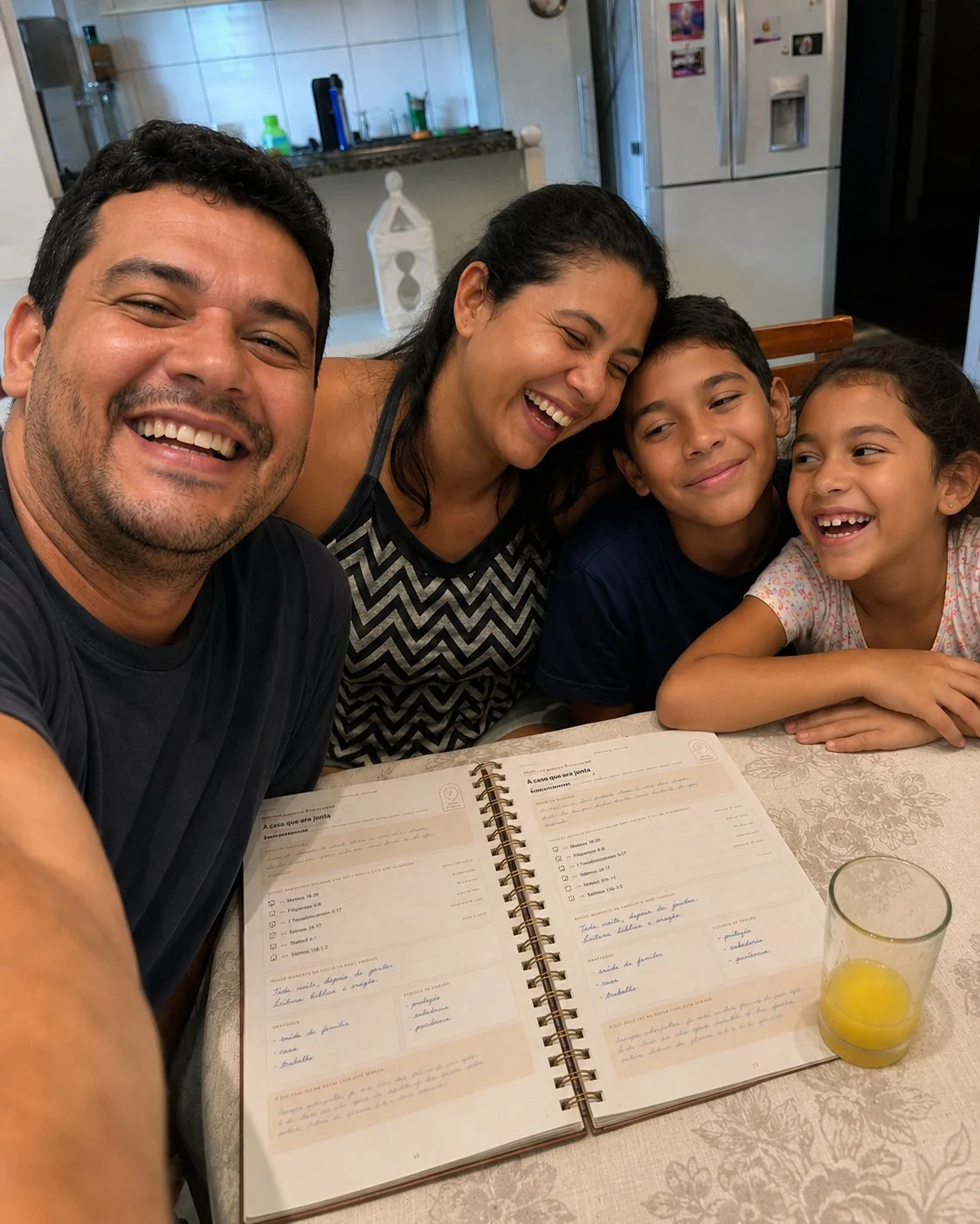 Família reunida à mesa sorrindo com o planner devocional Família Firmada
